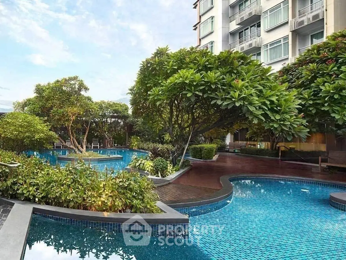 Luxurious residential building with stunning pool and lush garden view.