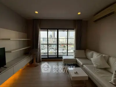 Spacious living room with modern decor and city view, featuring a comfortable sofa and sleek shelving.