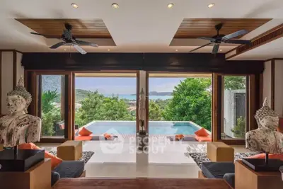 Luxurious living room with stunning pool and ocean view, featuring elegant decor and ceiling fans.