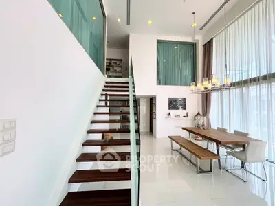 Luxurious modern living room with high ceilings and elegant staircase in a contemporary home.