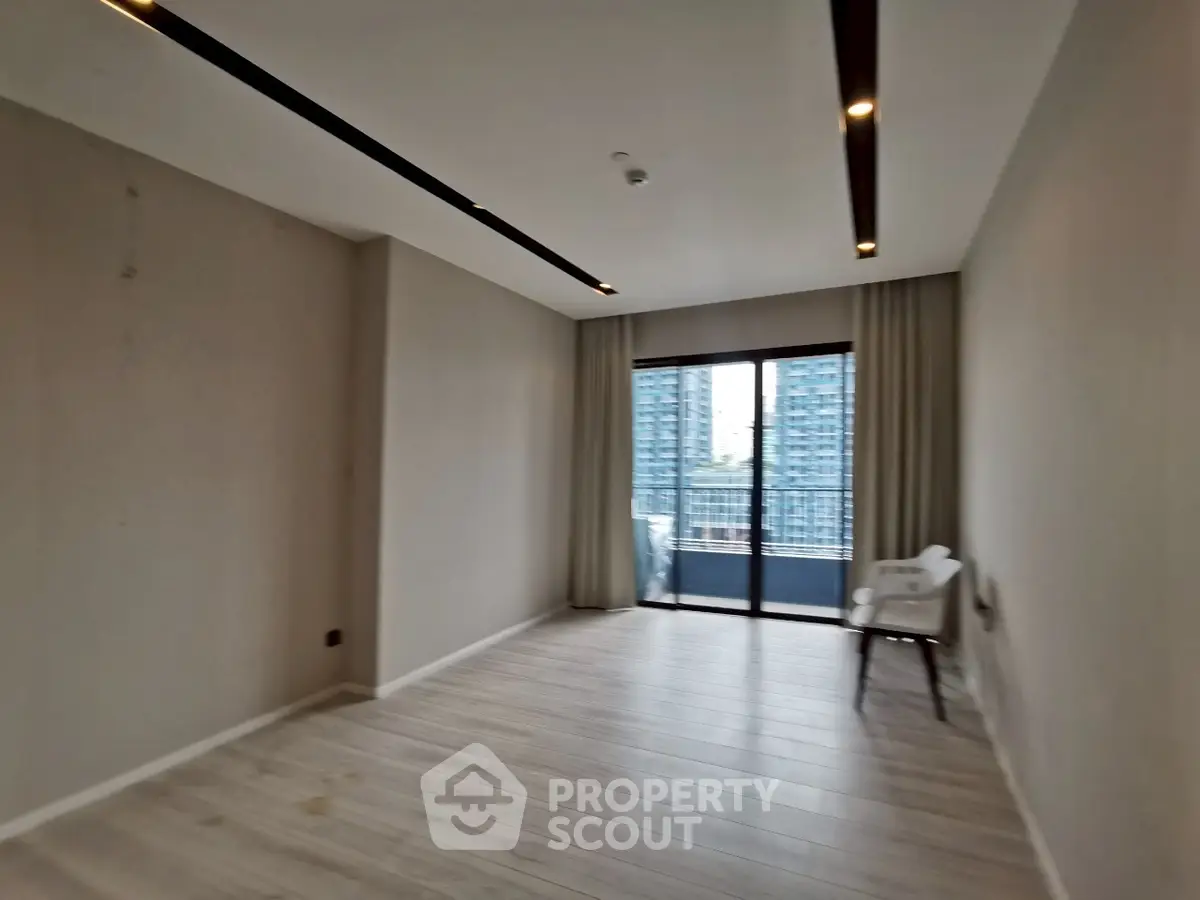 Spacious modern living room with large windows and balcony view in urban apartment.