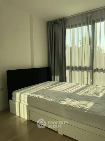 Bright bedroom with large window and modern bed frame, perfect for relaxation and comfort.