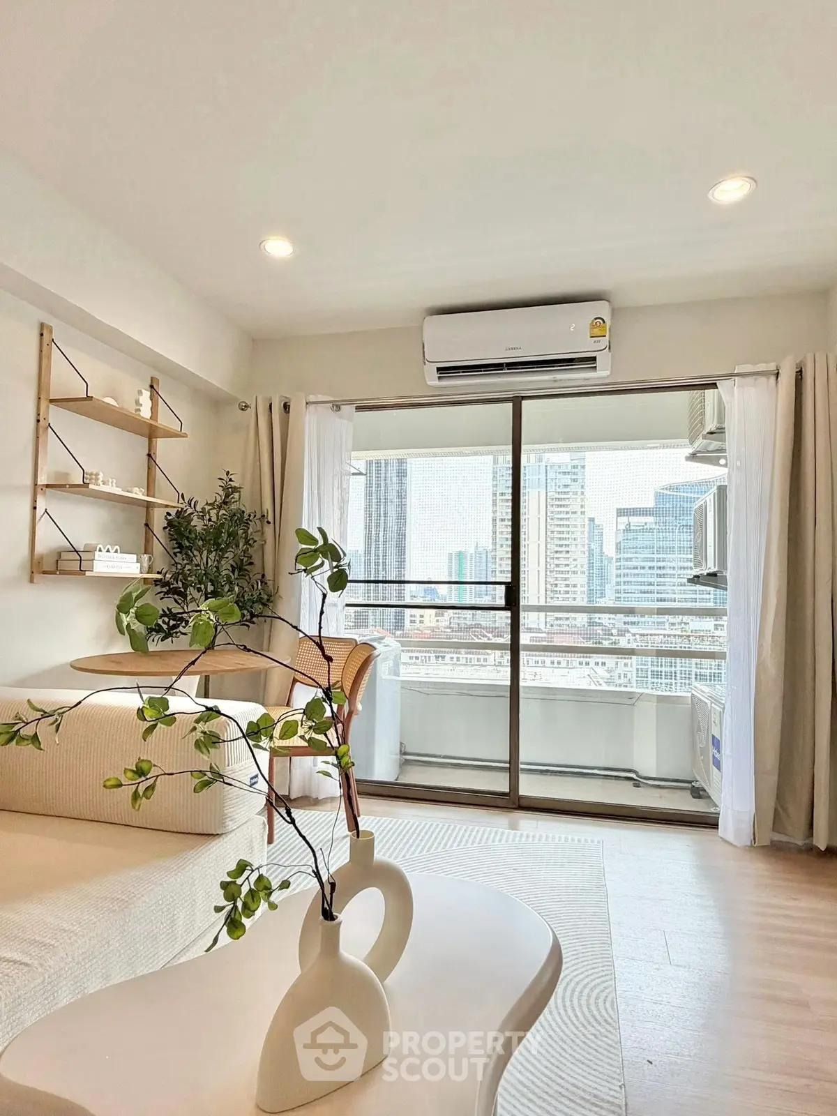 Modern living room with balcony and city view, featuring elegant decor and natural light.