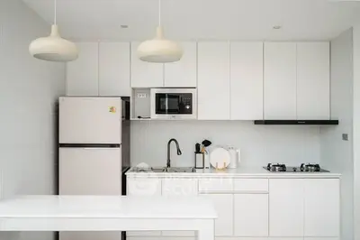 Modern kitchen with sleek white cabinets and gas stove, featuring minimalist design and ample storage.