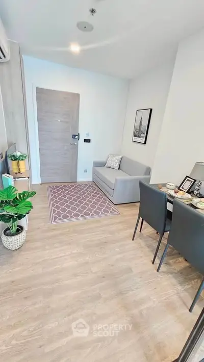 Modern living room with cozy sofa, dining area, and stylish decor in a compact apartment.