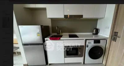 Modern compact kitchen with appliances including fridge, microwave, and washing machine.