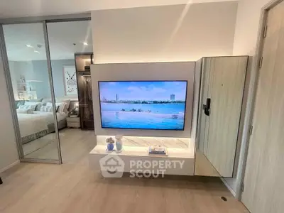 Modern living room with sleek TV setup and view into stylish bedroom