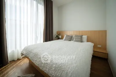 Cozy bedroom with large window and modern decor, perfect for relaxation and comfort.
