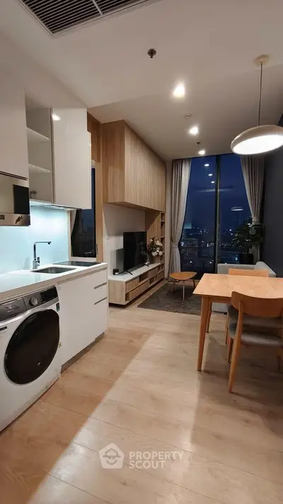 Modern open-plan living room with city view, featuring sleek kitchen and cozy dining area.