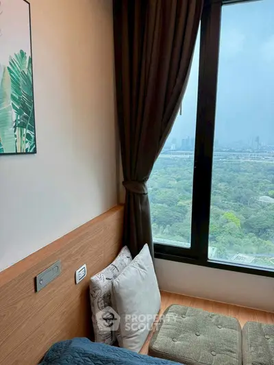 Cozy bedroom with large window offering stunning city and park views, perfect for relaxation.