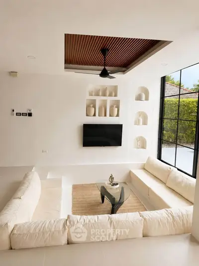 Luxurious sunken living room with modern decor and large windows offering garden views.