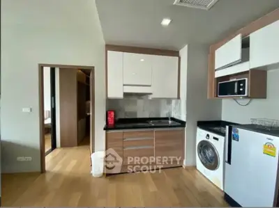 Modern kitchen with sleek cabinetry, washing machine, and microwave in a stylish apartment.