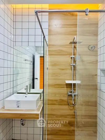 Modern bathroom with stylish shower and sink, featuring wood accents and sleek design.