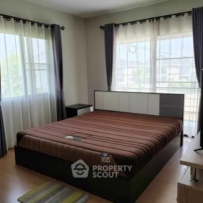Spacious bedroom with large windows and modern decor, offering ample natural light and a cozy atmosphere.