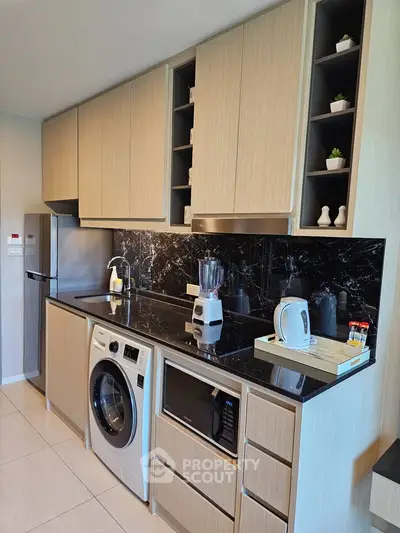 Modern kitchen with sleek cabinetry, black marble backsplash, and built-in appliances.