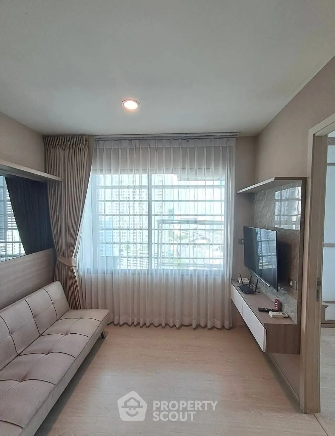 Modern living room with sleek furniture and large window offering city view