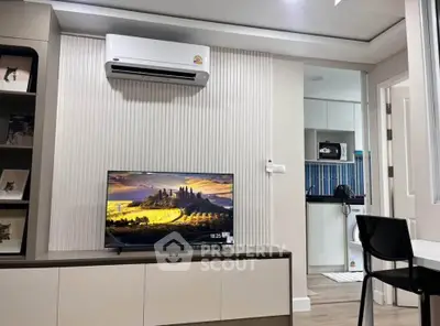 Modern living room with TV and air conditioning, adjacent to a compact kitchen area.