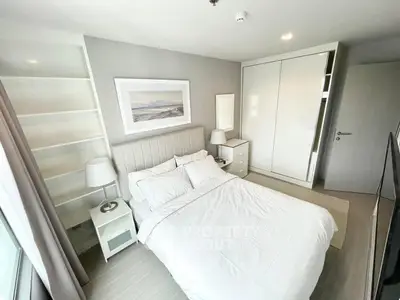Modern bedroom with white decor, built-in wardrobe, and large window for natural light.