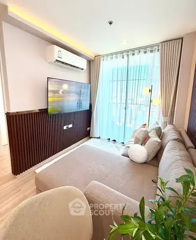 Modern living room with large sofa, wall-mounted TV, and floor-to-ceiling windows.