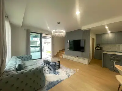 Modern living room with elegant decor and open layout, featuring a stylish sofa and large TV.