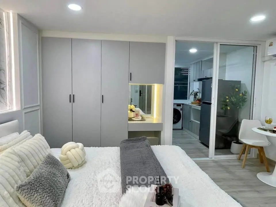 Modern bedroom with sleek design and open kitchen layout, featuring stylish decor and ample natural light.