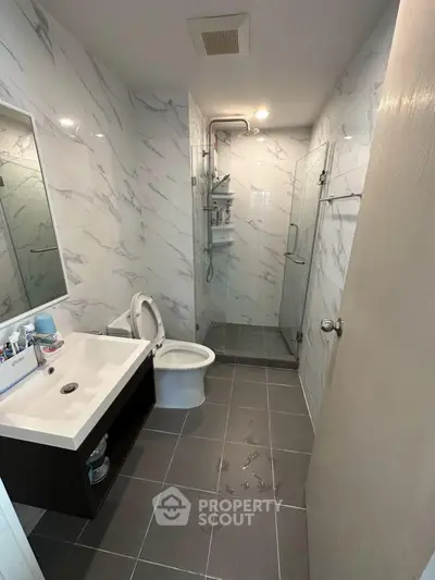 Modern bathroom with sleek design, featuring a glass shower enclosure and elegant marble tiles.