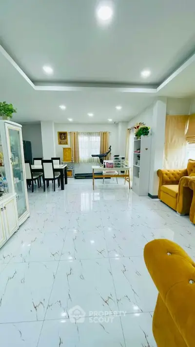 Spacious living room with elegant decor and dining area, featuring bright lighting and modern furnishings.
