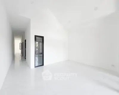Spacious minimalist interior with high ceilings and sleek white flooring, perfect for modern living.