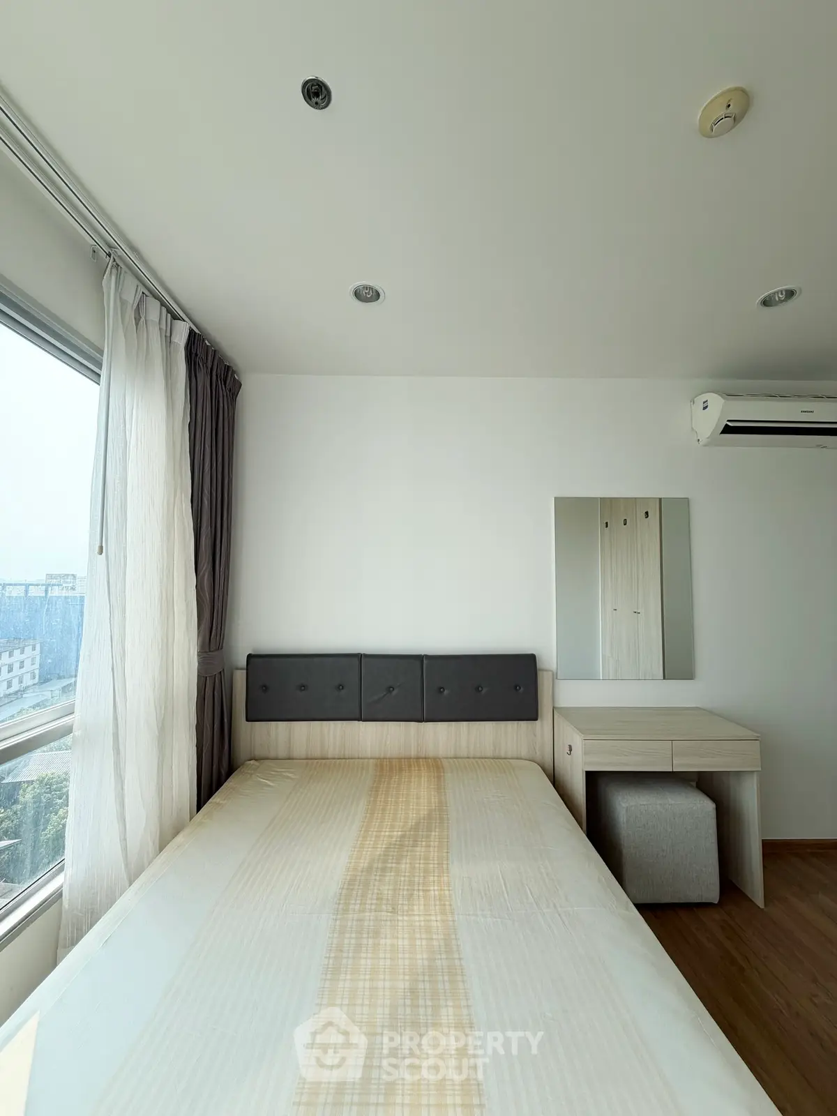 Bright and airy bedroom with modern furnishings and large window view.