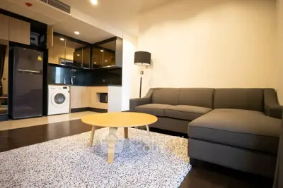 Modern living room with sleek kitchen, cozy sofa, and stylish decor in open-concept apartment.