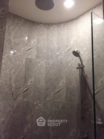 Luxurious marble-tiled shower with modern fixtures in elegant bathroom.