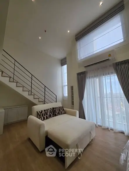 Spacious modern living room with high ceiling and large windows in a stylish apartment.