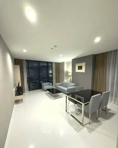 Modern living room with sleek furniture and city view through large windows.