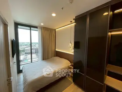 Modern bedroom with large window and stylish lighting in urban apartment.