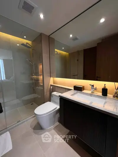 Modern bathroom with sleek design, featuring a glass shower and elegant vanity.