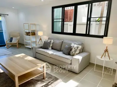 Bright and modern living room with stylish furniture and large window, perfect for relaxation.