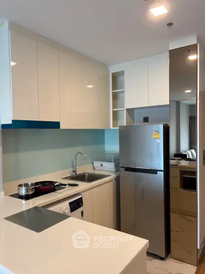 Modern kitchen with sleek cabinetry, stainless steel appliances, and a glass backsplash in a contemporary apartment.