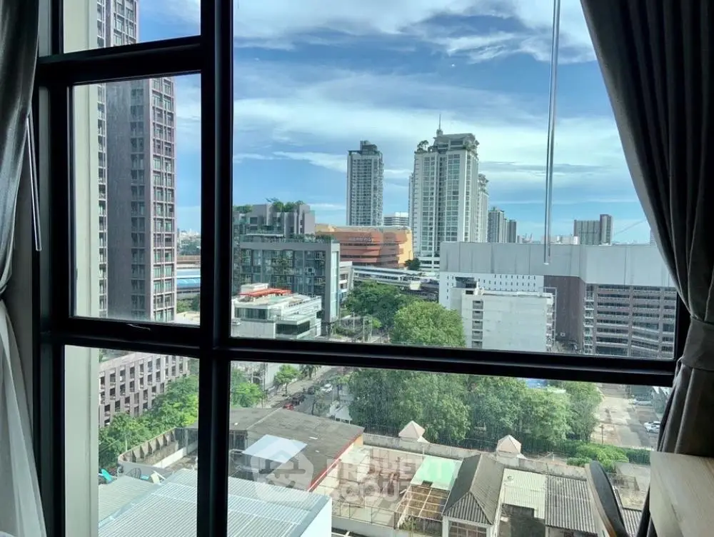 Stunning cityscape view from a high-rise apartment window, showcasing urban skyline and blue skies.
