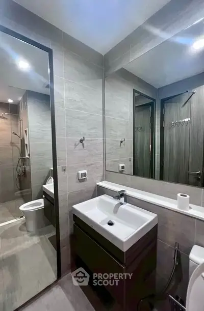 Modern bathroom with sleek fixtures and large mirror in contemporary apartment.