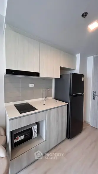Modern compact kitchen with sleek cabinetry and appliances in a stylish apartment.