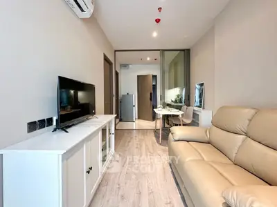 Modern living room with beige sofa and sleek TV unit, open layout to dining area.