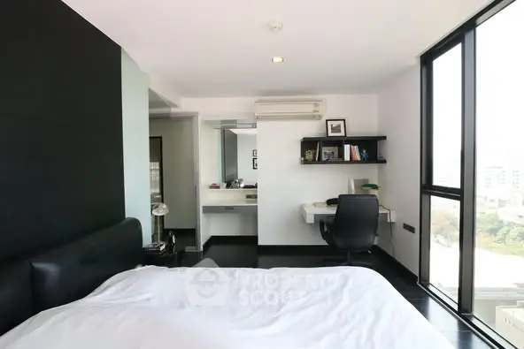 Modern bedroom with sleek design and large windows offering city views.