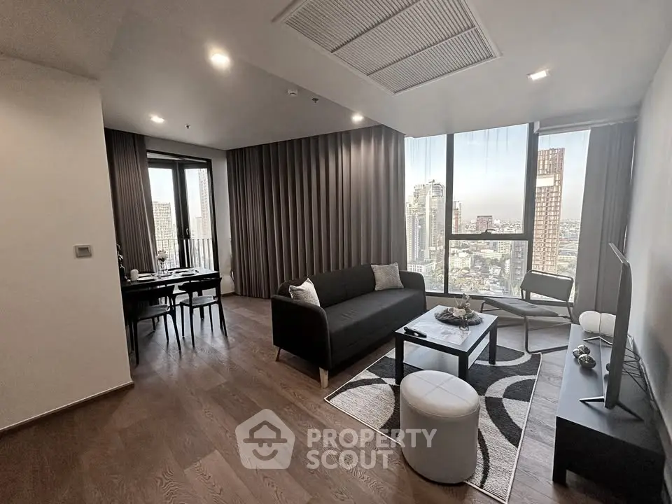 Modern living room with city view, stylish furniture, and elegant decor in a high-rise apartment.