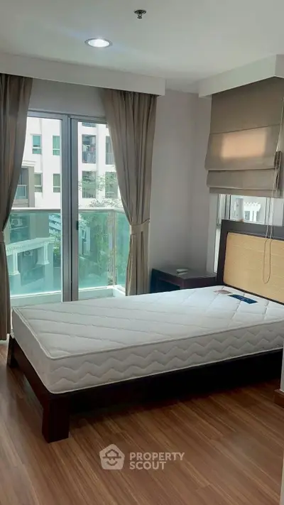 Spacious bedroom with large windows and wooden flooring in modern apartment