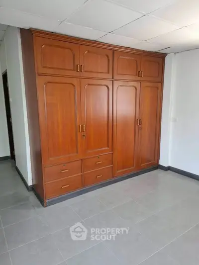 Spacious room with elegant wooden wardrobe and tiled flooring, perfect for storage solutions.