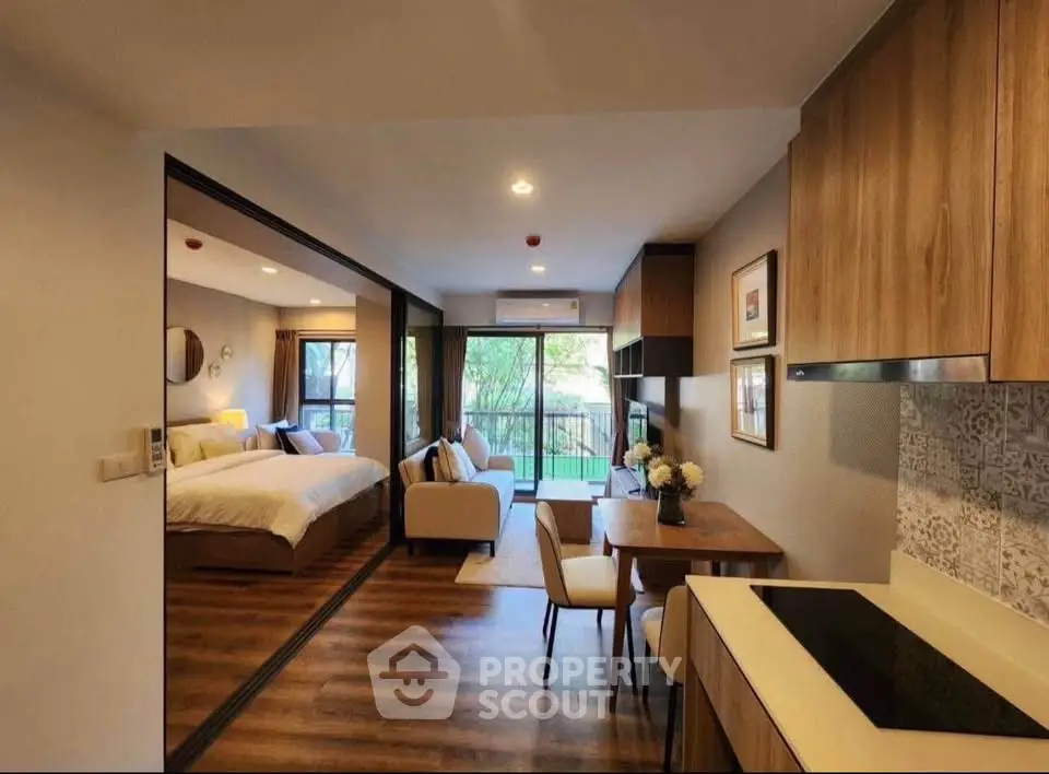 Modern open-plan studio apartment with stylish kitchen and cozy living area, featuring a view of lush greenery.