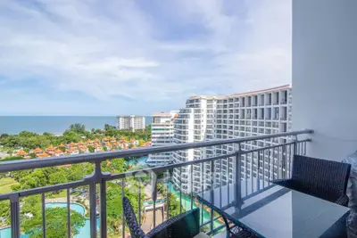 Stunning balcony view of ocean and modern high-rise buildings, perfect for relaxation.