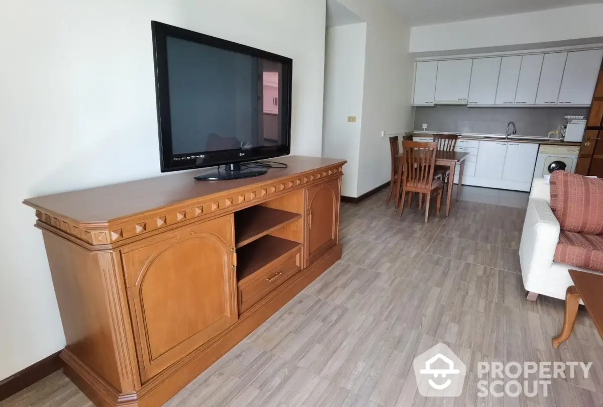 Spacious living area seamlessly connects to a white-themed kitchen, featuring ample natural light and modern comforts.