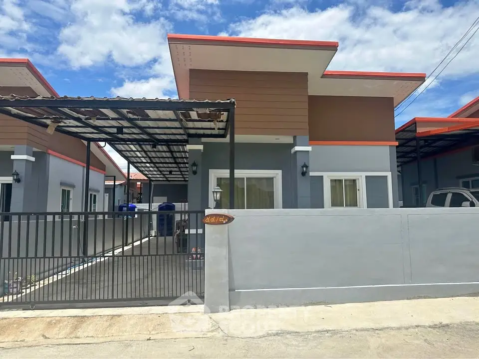 Modern single-story house with carport and gated entrance under a bright blue sky.