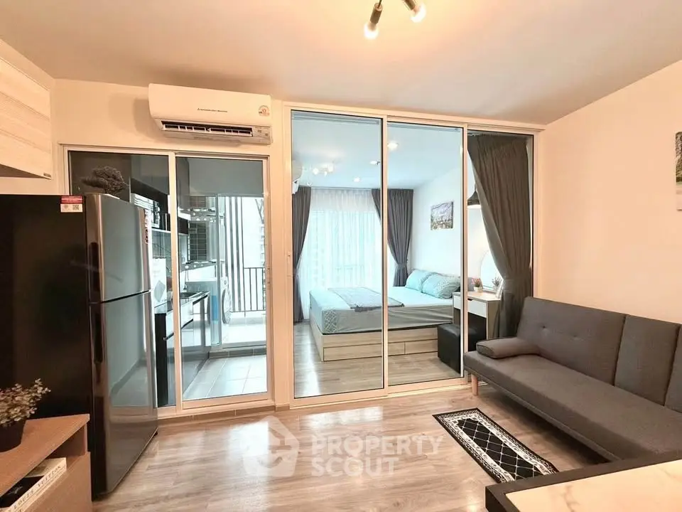 Modern apartment interior with open layout, featuring a cozy living room and bedroom separated by glass doors.